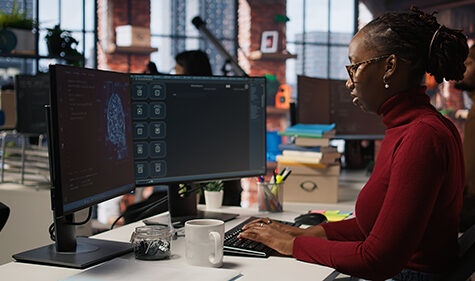 Silicon Valley venture programmer solving tasks with AI LLM chatbot using predictive technology. African american startup IT worker using PC to interact with generative model, camera A